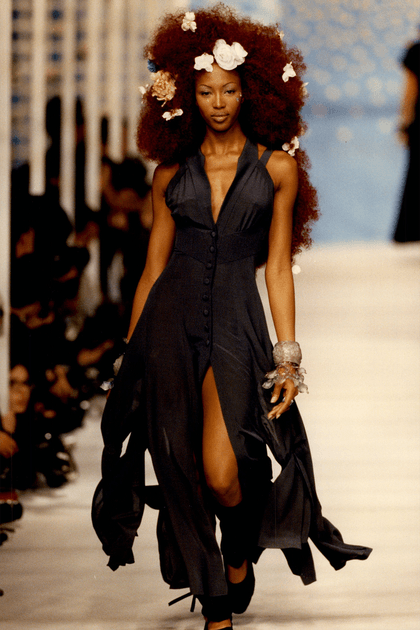 Naomi Campbell en robe noire et fleurs dans les cheveux