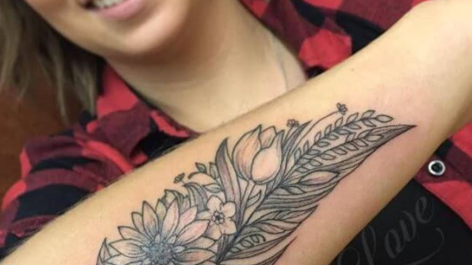 Tatouage plume et fleurs sur l'avant-bras