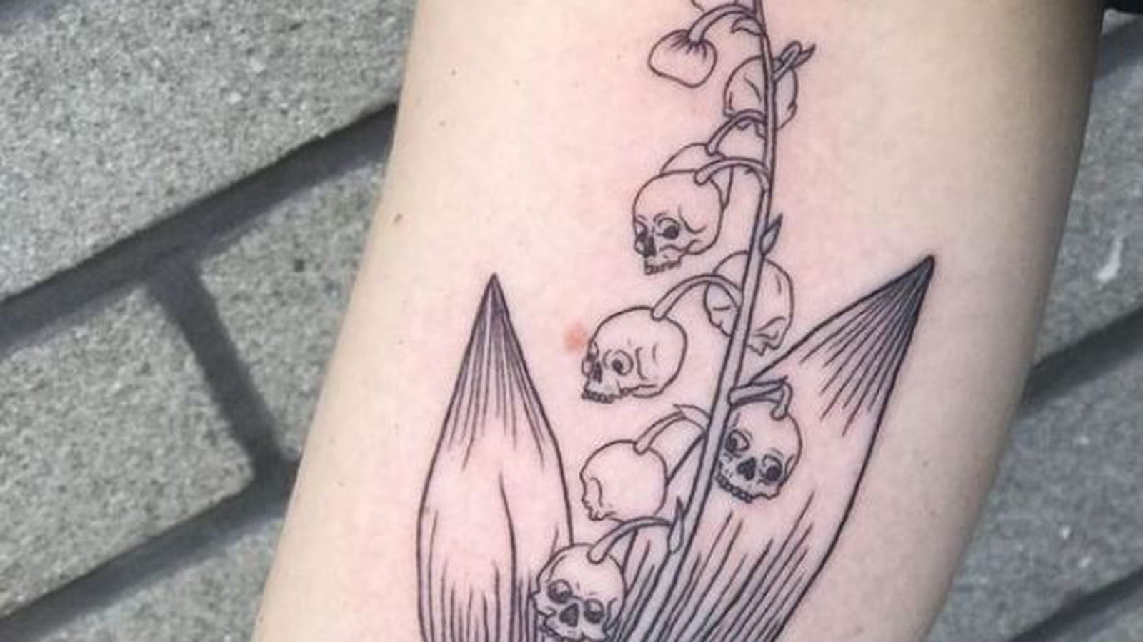 Têtes de mort et muguet sur le bras