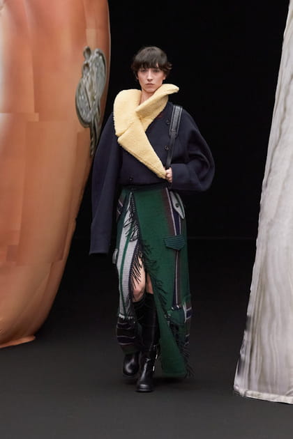 Jupe fendue &agrave; franges et manteau bleu marine avec col fa&ccedil;on peau de mouton aper&ccedil;us sur le d&eacute;fil&eacute; EENK