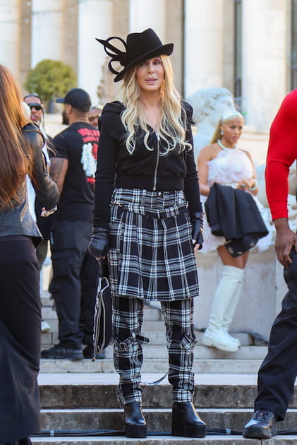 Cher en jupe et pantalon &agrave; carreaux avec un chapeau noir &agrave; plumes