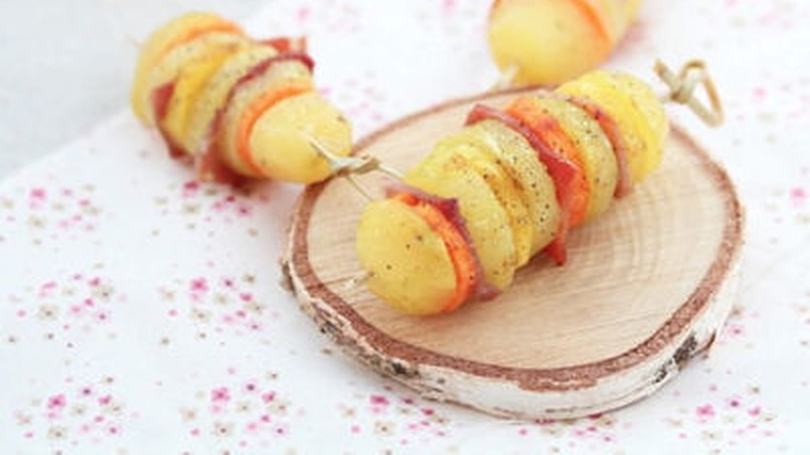 Brochettes de pommes de terre, carottes oranges et jaunes, jambon cru