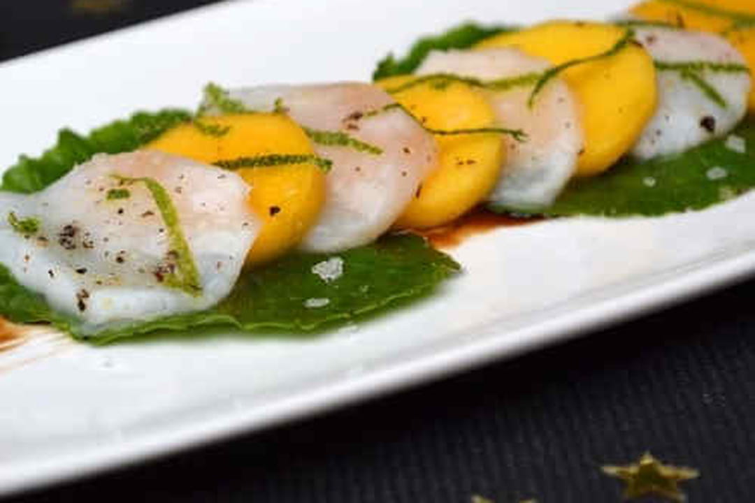 Carpaccio de saint-jacques marinées au citron vert, mangue et feuilles