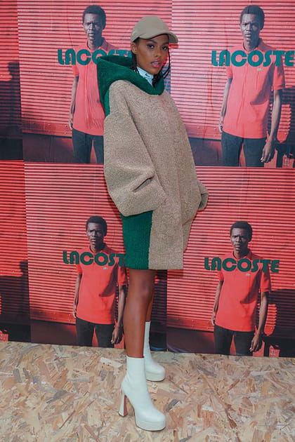 Tina Kunakey en robe pull beige et vert à capuche Lacoste