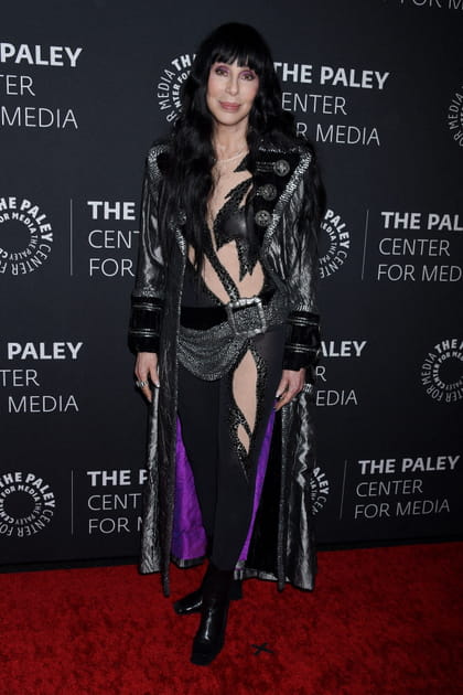 Cher en manteau noir long en cuir et tenue ajourée