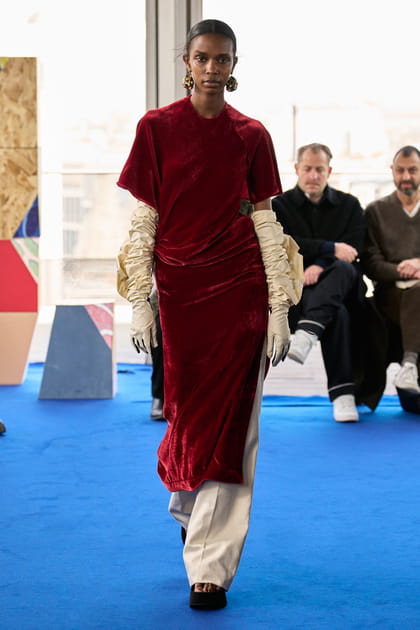 Robe rouge en velours fendue et pantalon beige aperçus