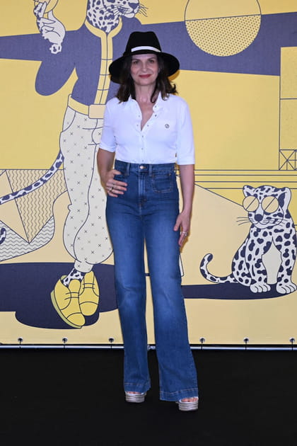 Juliette Binoche en chemise blanche ouverte et jean flare taille haute
