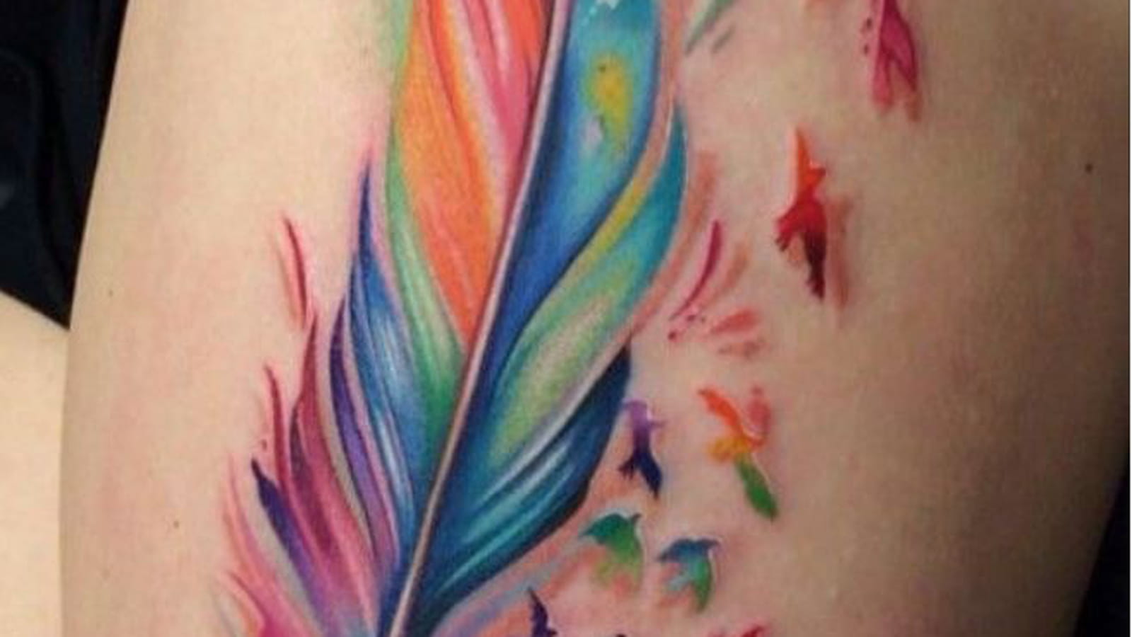 Tatouage plume colorée sur la cuisse