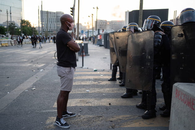 Un manifestant fait face aux forces de l'ordre, &eacute;quip&eacute;es avec boucliers et matraques