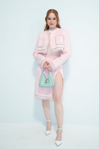 Madelaine Petsch en veste courte et jupe fendue roses en tweed et sandales blanches à brides au défilé Givenchy