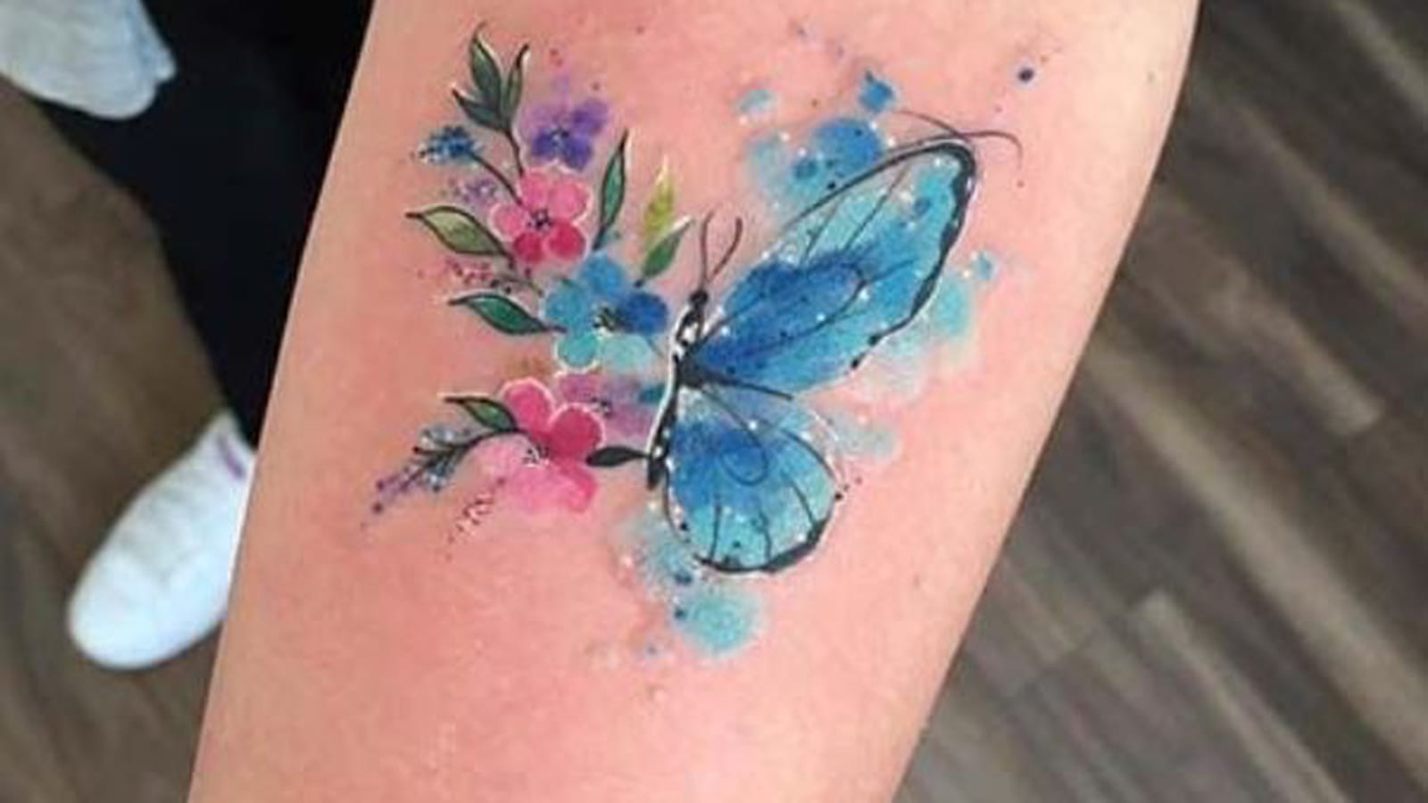 Demi-papillon et fleurs colorées sur l'avant-bras