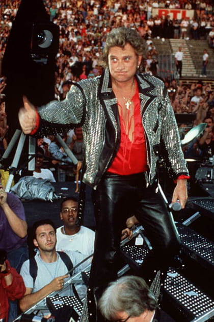 Johnny Hallyday en chemise satinée rouge, pantalon de cuir et veste brodée de strass