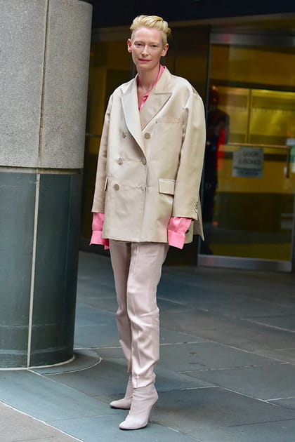 Tilda Swinton en blazer crème, chemise rose et pantalon pastel