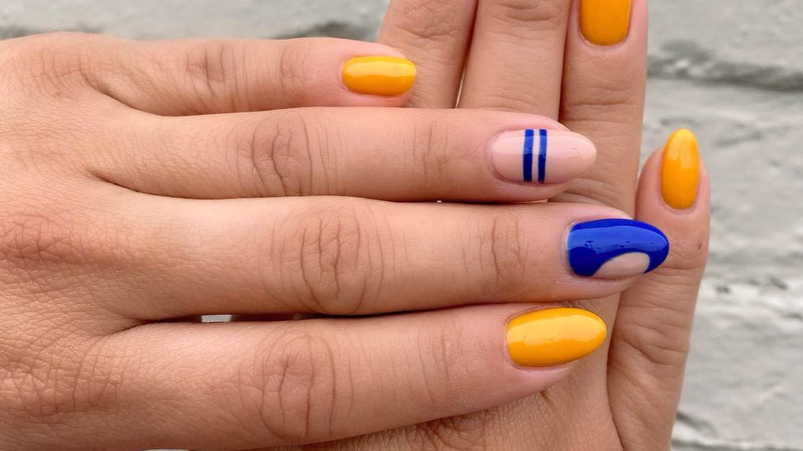 Une manucure géométrique jaune et bleue