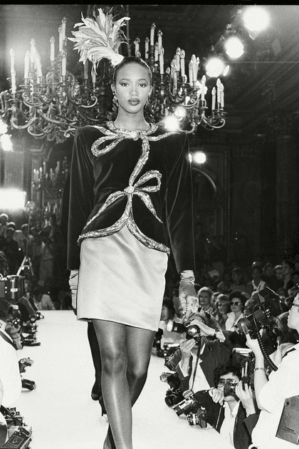 Naomi Campbell en jupe en satin et veste en velours à nœuds