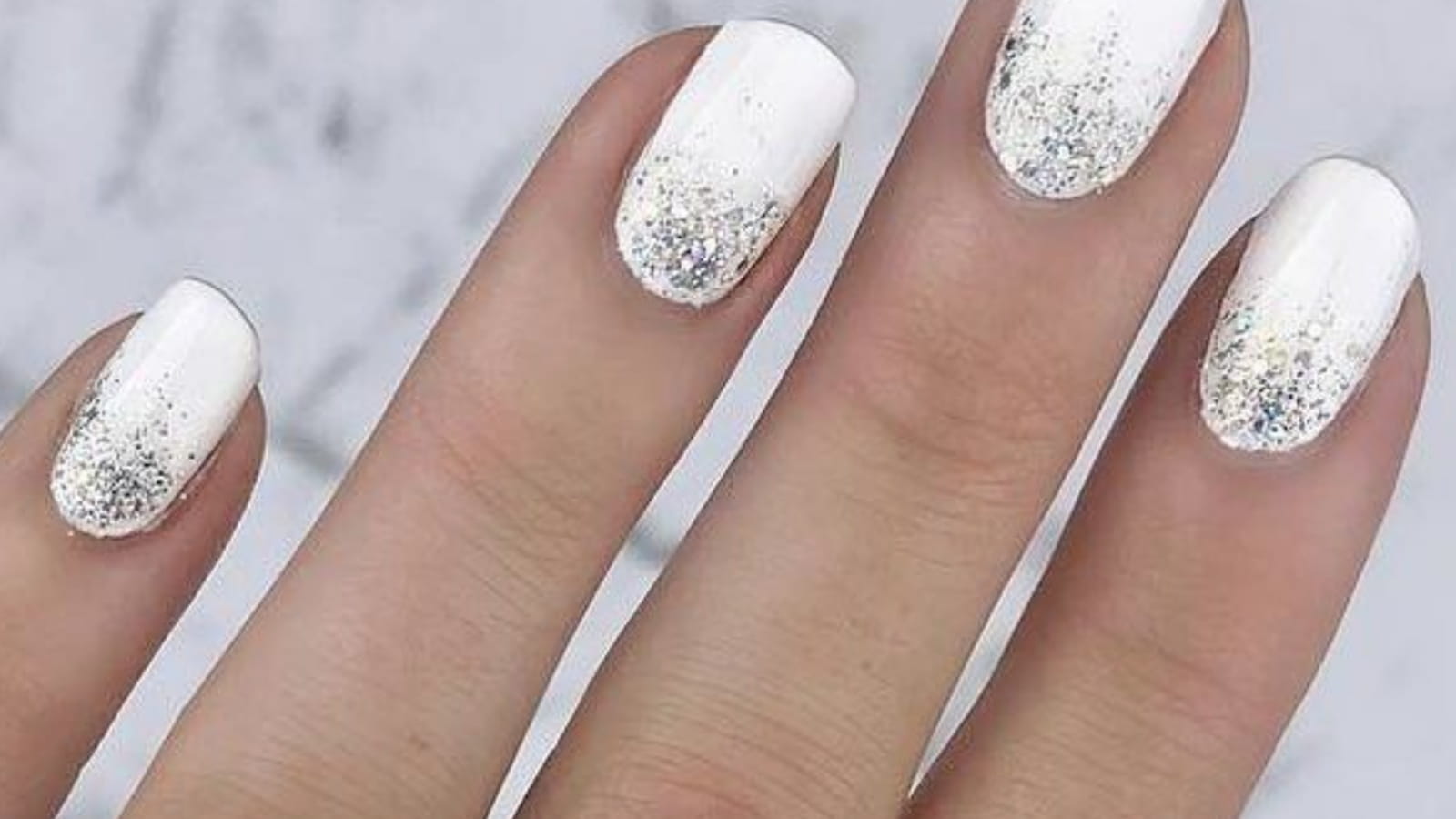 Des ongles blancs avec des paillettes argentées