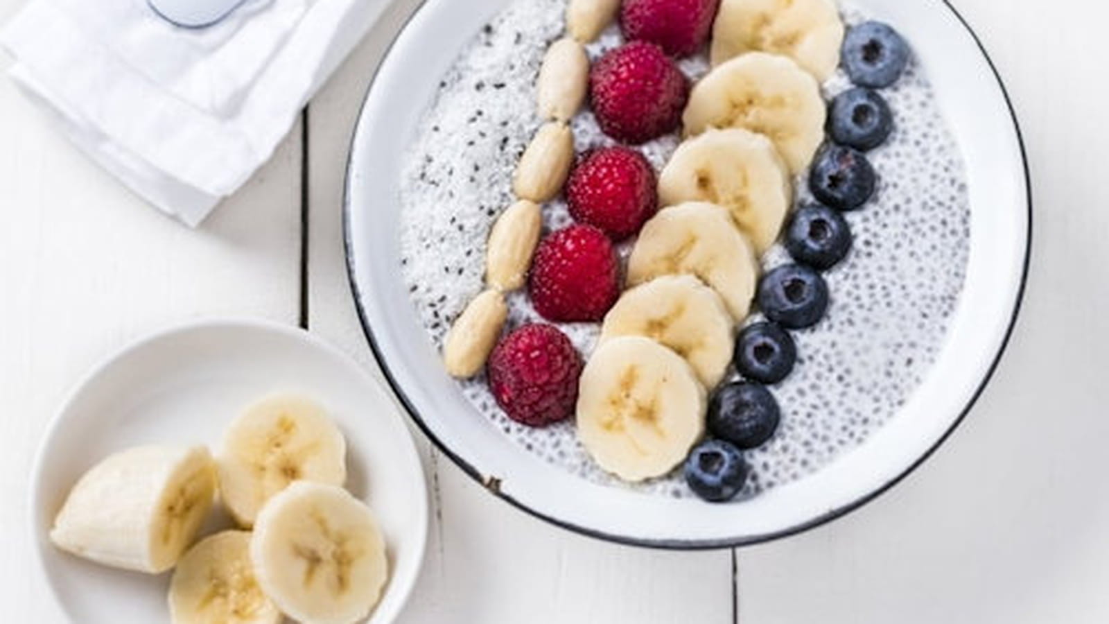 Porridge de graines de chia à la banane, aux amandes, aux framboises, à la poudre de noix de coco et aux myrtilles